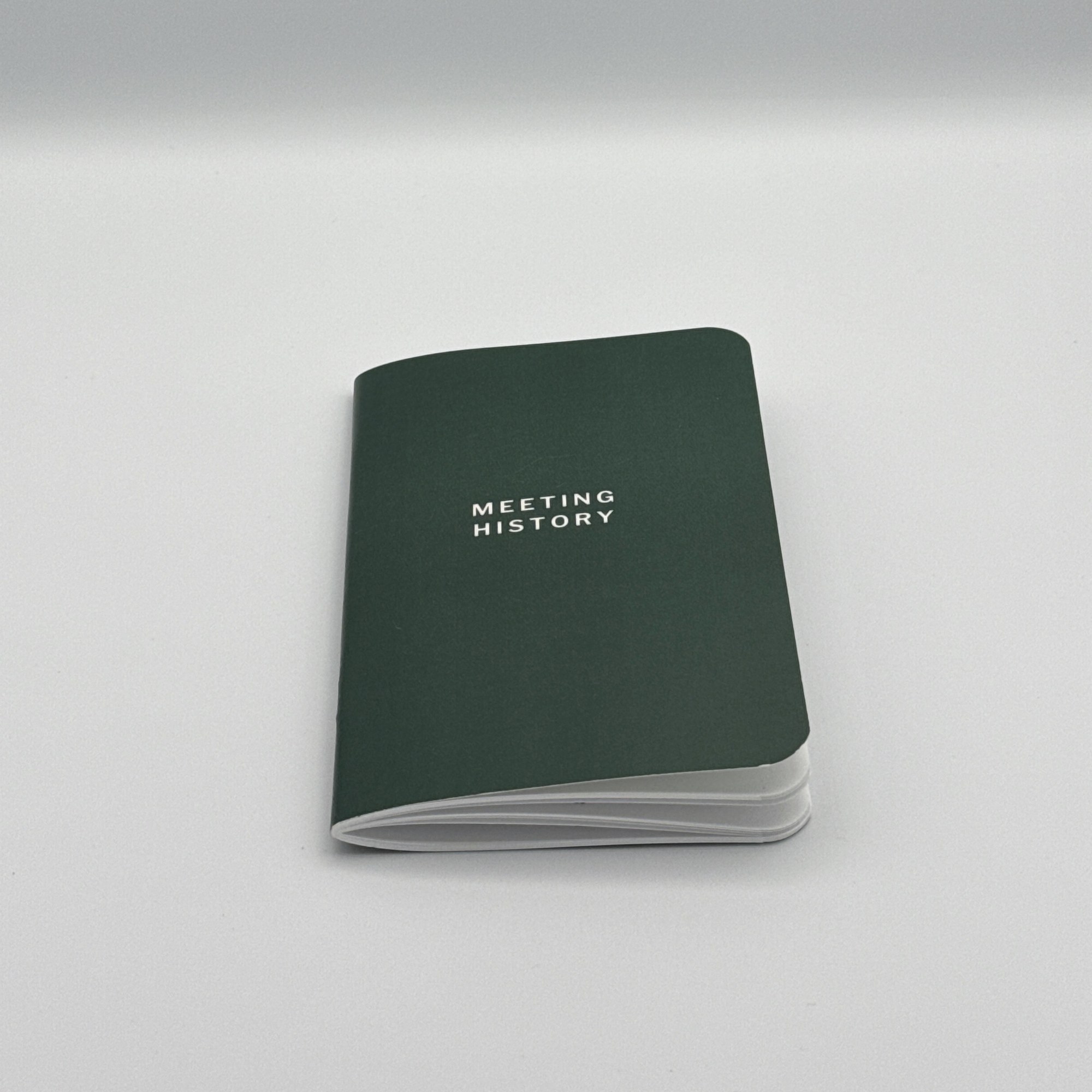 The Meeting History booklet, closed: dark green cover with MEETING HISTORY in white, photographed from a physical proof.
